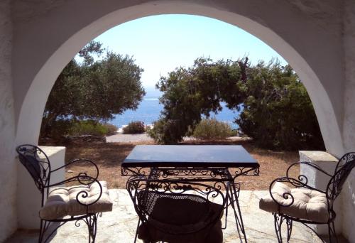 uma mesa e cadeiras num pátio com vista para o oceano em Stunning House in Sifnos Island Chrisopigi em Chrisopigi