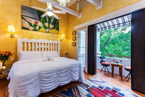 a bedroom with a white bed and a large window at Garlands Del Rio in Puerto Vallarta