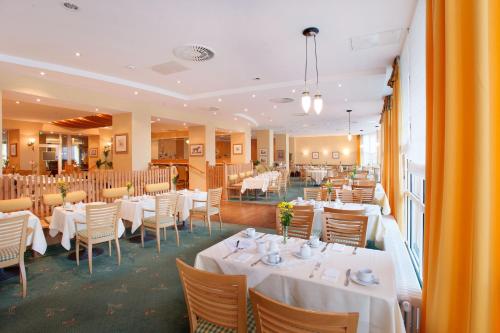 a dining room with white tables and chairs at H+ Hotel & SPA Friedrichroda in Friedrichroda