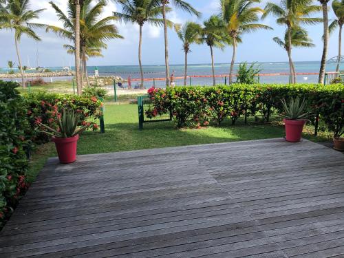 a wooden boardwalk with palm trees and a beach at Lauris - Résidence Savannah, 1 ou 2 Chambres avec cuve in Saint-François