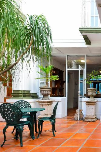 a patio with a table and chairs and a plant at Garlands Del Rio Riverside Boutique Hotel in Puerto Vallarta