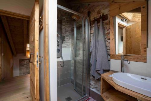 y baño con ducha acristalada y lavamanos. en Casa Ekharle - Affittacamere en Rotzo