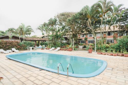 uma piscina num resort com árvores e um edifício em Flamboyant Hotel em Barra Velha