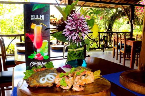 a table with a plate of food and a vase of flowers at Suchipakari Amazon Eco -Lodge & Jungle Reserve in Puerto Misahuallí