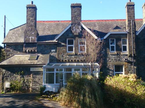 an old stone house with a greenhouse in front of it at Lovely Large home 10 Minute Walk to Barmouth Beach in Barmouth