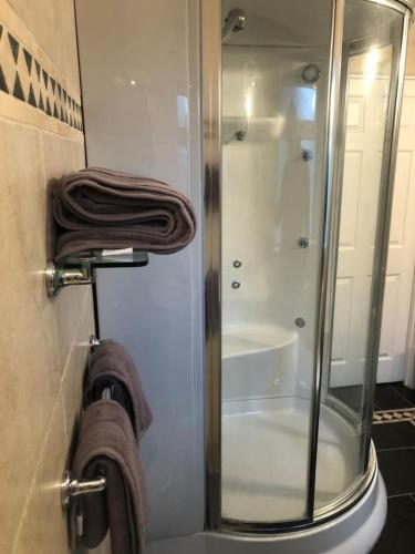 a bathroom with a glass shower stall with towels at Discreet luxury Super house! in Gleann Maghair