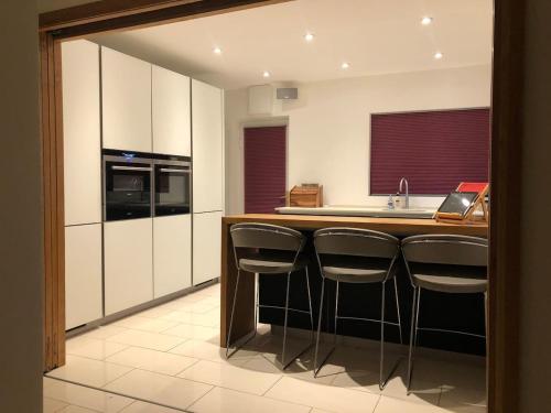 a kitchen with a island with bar stools at Discreet luxury Super house! in Gleann Maghair