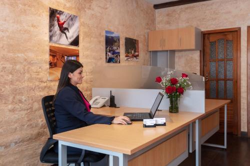 a woman sitting at a desk with a laptop at Casa del Balcon in Baños