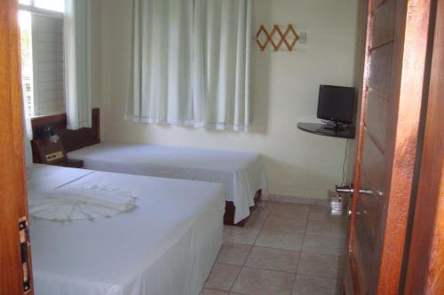 a hotel room with two beds and a television at BOULEVARD DA PRAIA Apart Hotel Beira mar in Porto Seguro