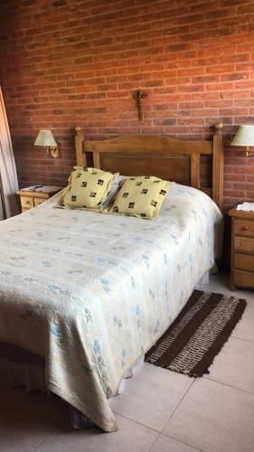 a bedroom with a bed and a brick wall at DUPLEX Casa 100 m2 CARILO HOUSE Complejo Residencial Sin Serv in Carilo