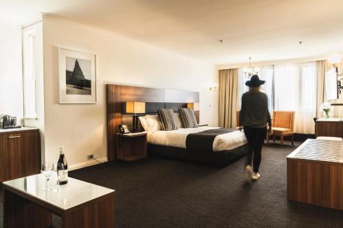 a woman walking through a hotel room with a bed at Lenna Of Hobart in Hobart