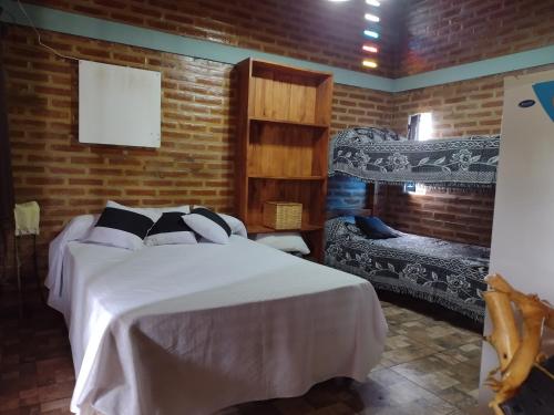 a bedroom with a white bed and a brick wall at La Pirca in Nono