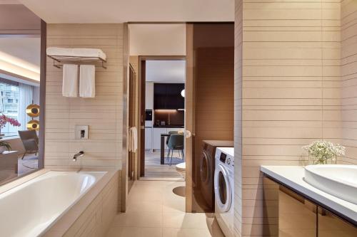 y baño con bañera, lavabo y lavadora. en Pan Pacific Serviced Suites Orchard, Singapore, en Singapur