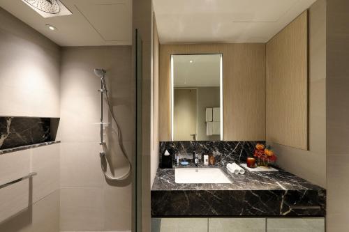 La salle de bains est pourvue d'un lavabo et d'un miroir. dans l'établissement Pan Pacific Serviced Suites Orchard, Singapore, à Singapour
