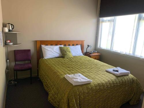 a bedroom with a bed with two towels on it at Catlins Inn in Owaka