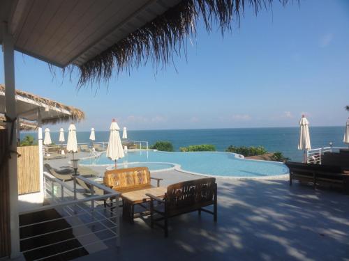 a swimming pool with a table and chairs and umbrellas at High Life Bungalow in Haad Yao