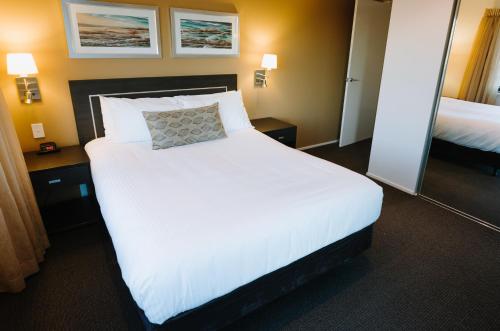 a hotel room with a large white bed with a pillow at Ramada Hotel & Suites by Wyndham Ballina Byron in Ballina