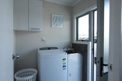 a small kitchen with a sink and a refrigerator at Rose Apartments Central Rotorua- Accommodation & Private Spa in Rotorua