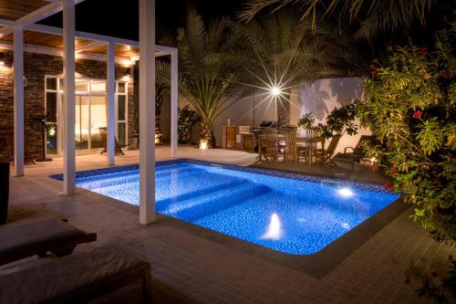 a swimming pool in a backyard at night at Dar 66 Pool Chalets with Jacuzzi in Ras al Khaimah