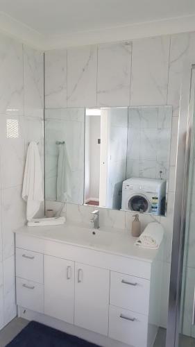 a white bathroom with a sink and a microwave at Alkion Villa in Wagga Wagga