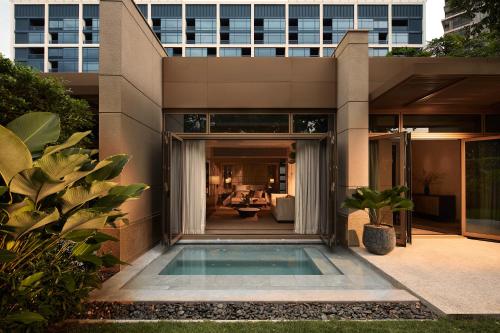 a house with a swimming pool in front of a building at Capella Bangkok in Bangkok