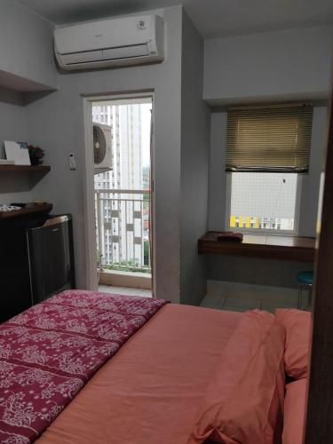 a bedroom with a bed with a red bedspread and a window at The Studio Furnish Springlake Summarecon BCBD with an Amazing View for Healing in Rawabugel