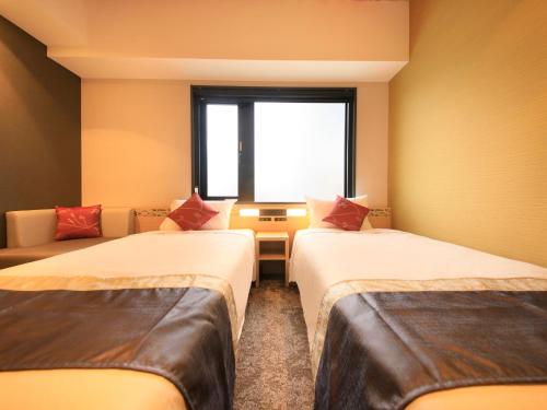 a room with two beds and a window at The Hedistar Hotel Kyoto Nijo Comic & Books in Kyoto