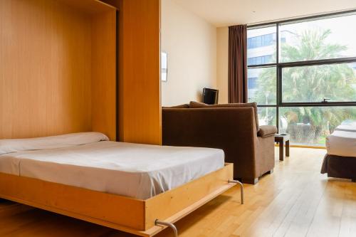 
a bedroom with a bed, chair and a window at Aparthotel Wellness in Paterna
