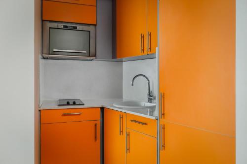 a kitchen with orange cabinets and a sink at Aparthotel Wellness in Paterna