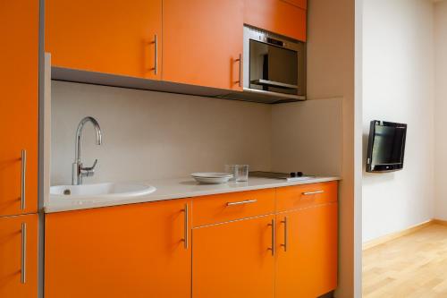 pomarańczowa kuchnia ze zlewem i kuchenką mikrofalową w obiekcie Aparthotel Wellness w mieście Paterna