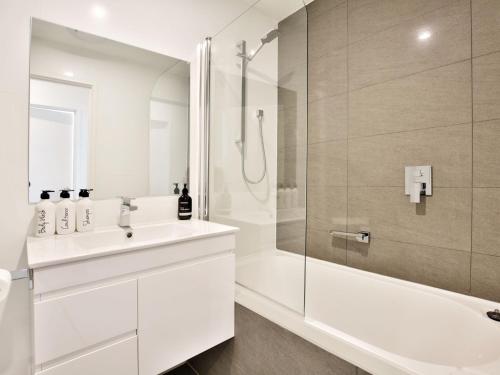 a white bathroom with a shower and a sink at Husky Sands I Pet Friendly I 5 Mins Walk to Beach in Huskisson