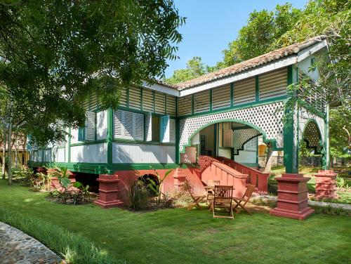 a green and white house with a yard at Temple Tree Resort in Pantai Cenang