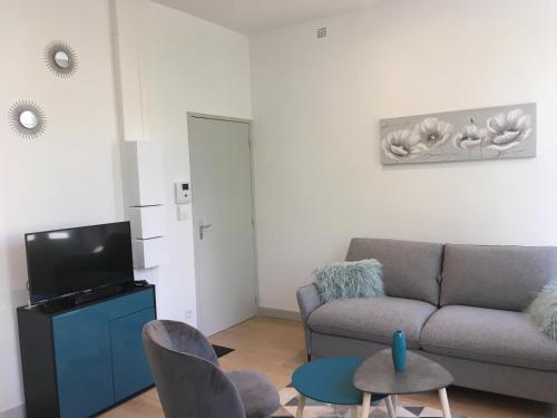 un salon avec un canapé, des chaises et une télévision dans l'établissement L ORATOIRE 1, à La Rochelle