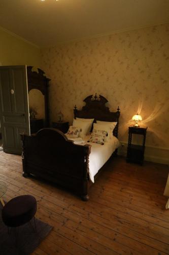 a bedroom with a large bed with a wooden headboard at Domaine de Champ rose in Saint-Laurent-de-Belzagot
