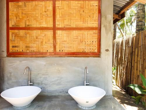 a bathroom with two white sinks on a wall at Higala Hostel Siargao in General Luna