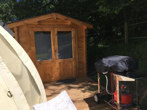 a wooden shed with a door and a cart in front at Yourte et son bain nordique in Fréchet-Aure