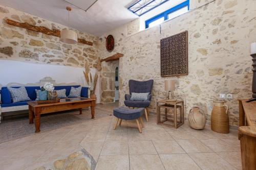 a living room with stone walls and blue chairs at Anna's Villa in Mesi Village in Agia Triada