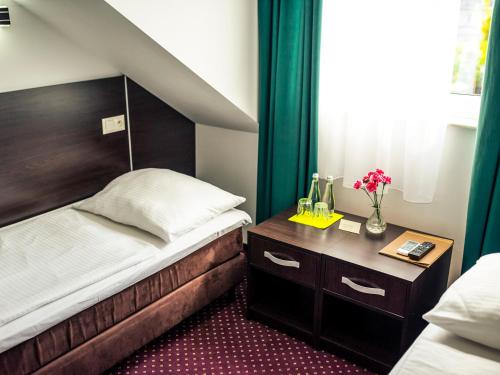 a bedroom with a bed and a table with flowers at Hotel Mużakowski in Łęknica