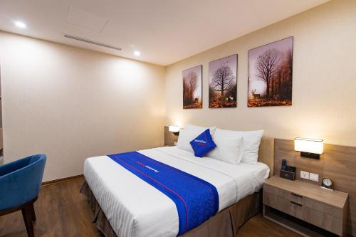 a hotel room with a bed and a blue chair at Sunshine Hotel Móng Cái in Móng Cái