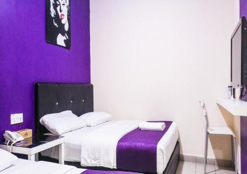a room with two beds and a purple wall at Biz Hotel in Batu Pahat