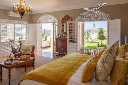 a bedroom with a large bed and a living room at Grand Lux Boutique Manor in Hermanus