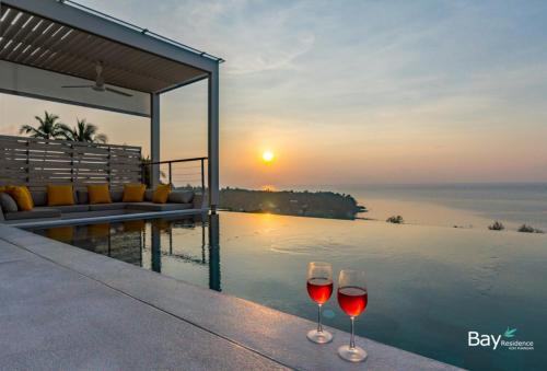 
a glass of wine sitting next to a body of water at Bay Villas Koh Phangan in Salad Beach
