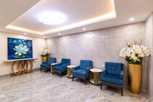 a waiting room with blue chairs and tables and a painting at Sunshine Hotel Móng Cái in Móng Cái