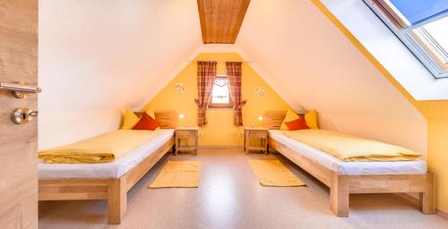 two beds in a attic room with yellow walls at Bartlhof-Ferienwohnungen-Zimmer in Burglengenfeld