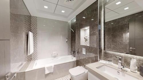 a bathroom with a tub and a toilet and a sink at SUHA Mina Rashid Hotel Apartments in Dubai