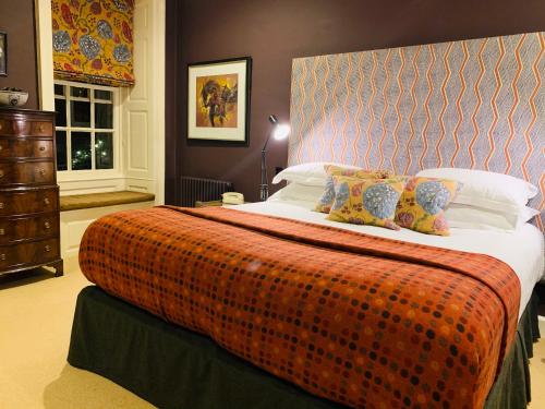 a bedroom with a large bed with an orange blanket at The Close Hotel in Tetbury