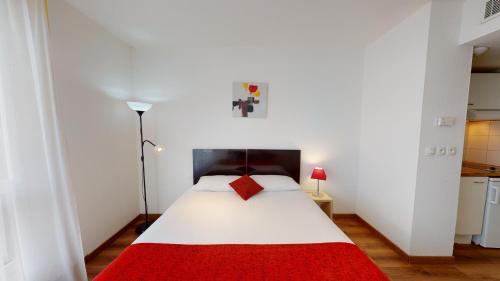 - une chambre avec un lit blanc et une couverture rouge dans l'établissement Alezan Hôtel & Résidence, à Toulouse