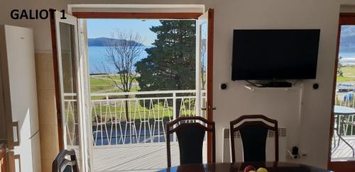 a room with a door open to a balcony with a television at Apartmani Galiot in Igalo