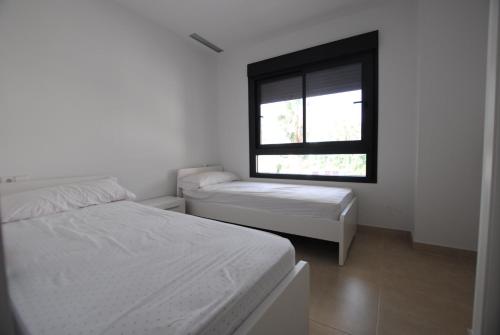 Cette chambre blanche dispose de deux lits et d'une fenêtre. dans l'établissement 196 Terrazas de Las Marinas - Deniasol, à Dénia