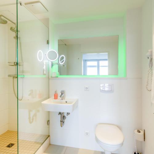 a bathroom with a toilet and a sink and a mirror at bedpark Stellingen in Hamburg